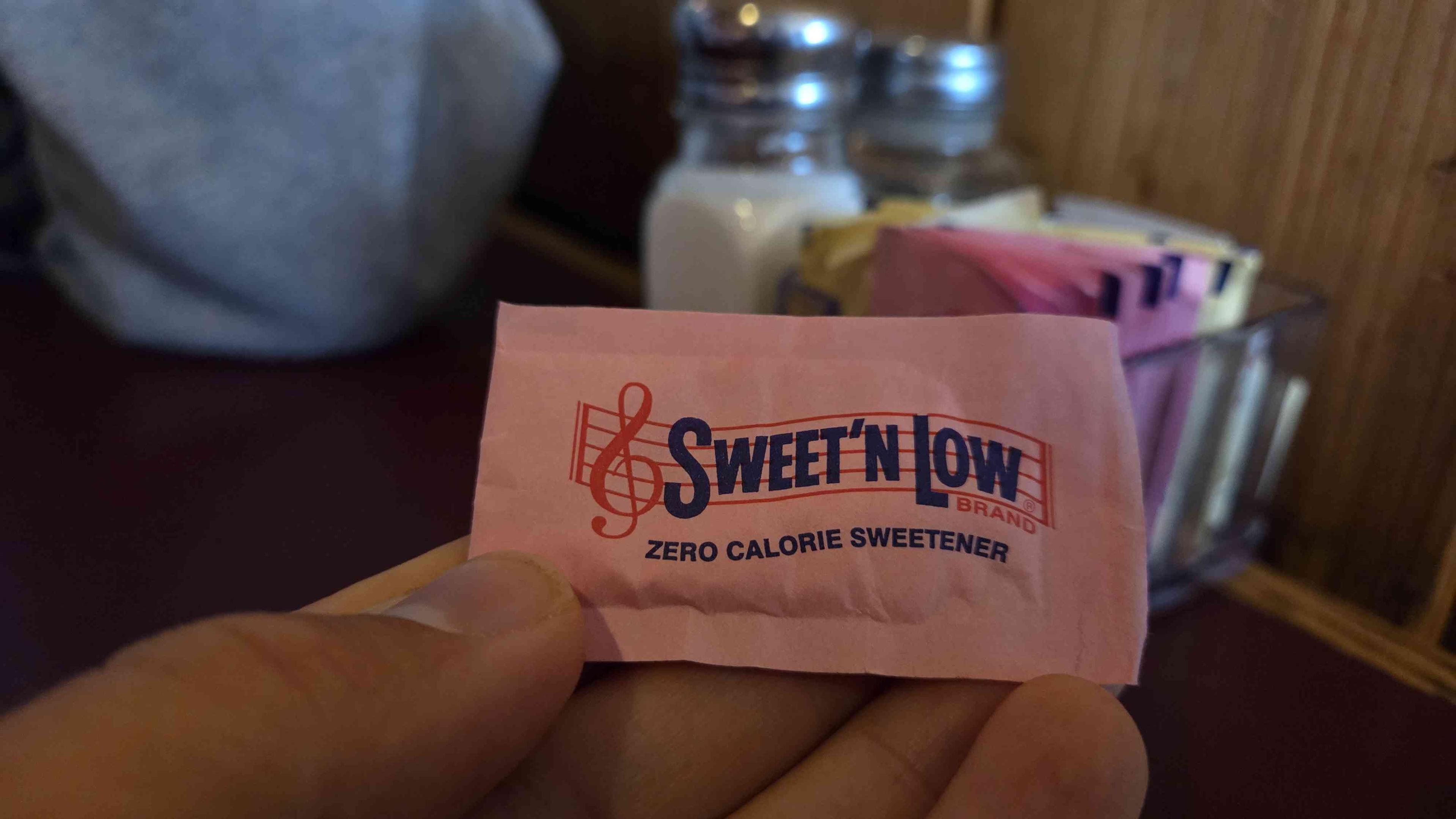 A close-up photo of a packet of Sweet 'n Low artificial sweetener, with a logo featuring a treble clef.