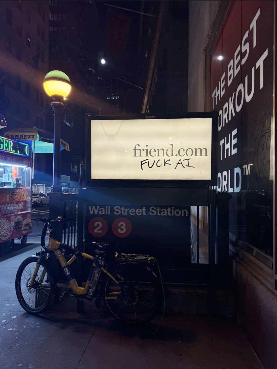 Photo of a subway ad for AI startup friend, graffiti over it says “fuck AI”. Photo is taken outside of the wall st station