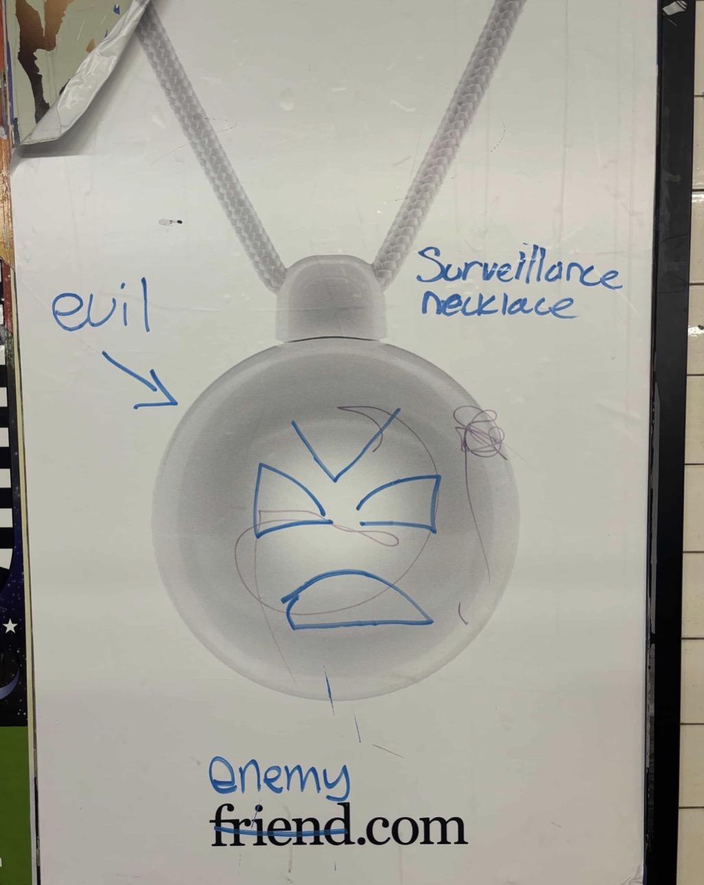 Photo of a subway ad for AI startup friend, with the pendant. Graffiti over it has an angry face on the pendant, says “evil” and “surveillance necklace” and the word friend is crossed out by “enemy”