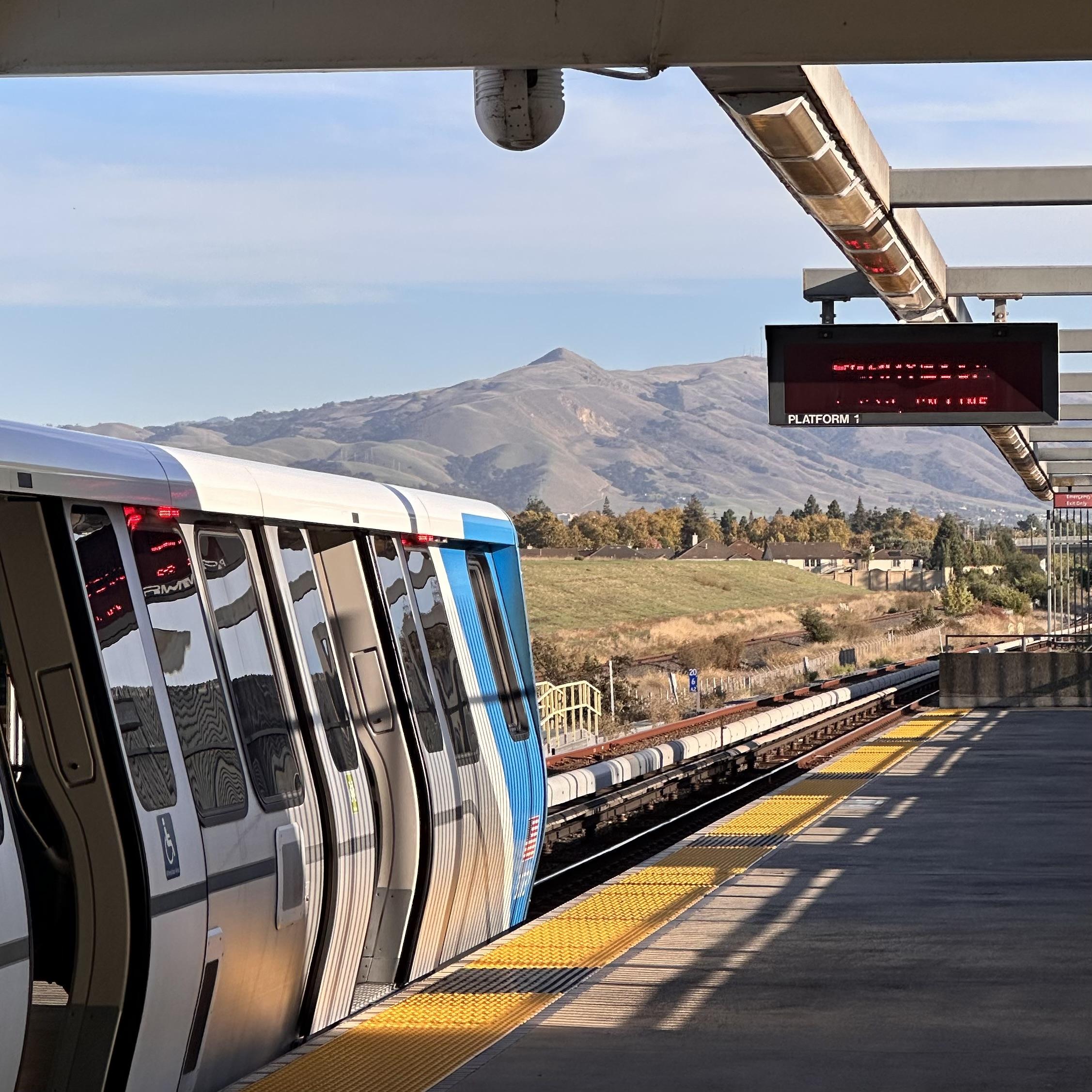 A photo of BART at Union city station. In the background, a small hill