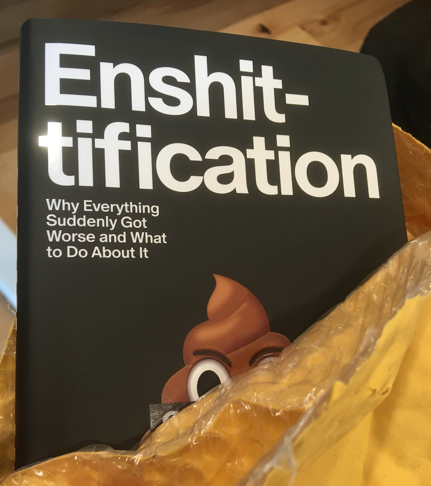 The cover of Cory Doctorow's latest book, "Enshitification". It is black background with bold, white text and a cheeky poop emoji, peeking out of the mail package it arrived in. More about the author and the book is available at https://pluralistic.net/