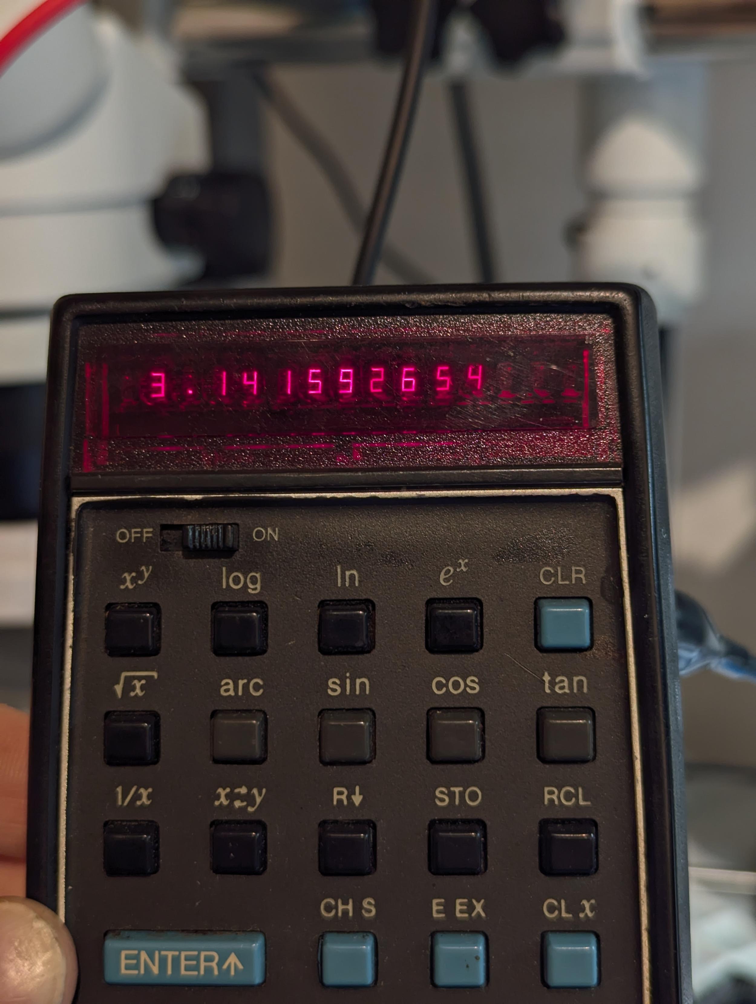 An early 1970s HP35 calculator showing the value of pi in sharp red light.