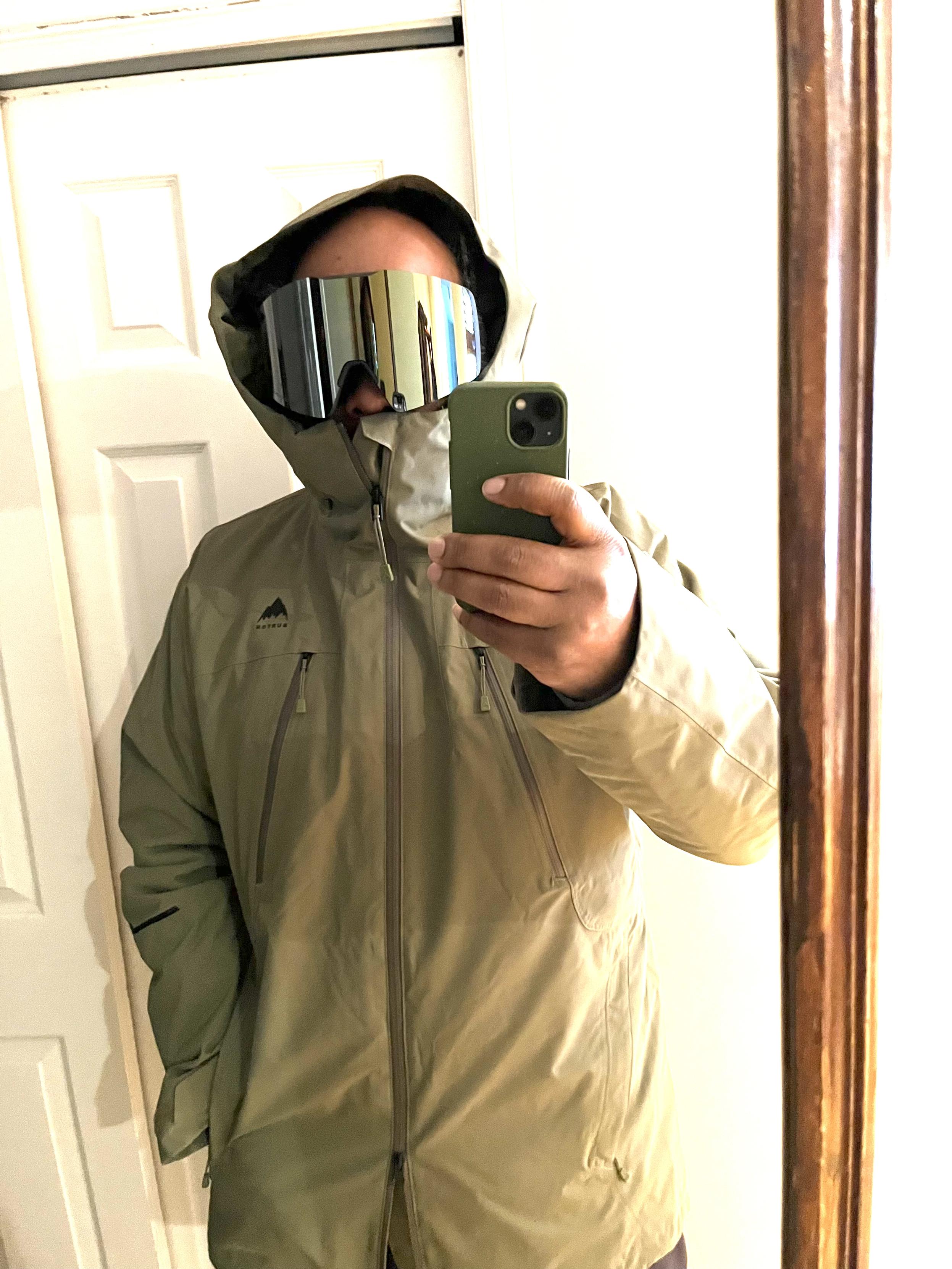mirror selfie wearing light green winter jacket and dark green wraparound snow goggles