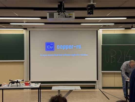 Photo of a small stage with a screen saying: copper-rs An open source Rust first software engine for robotics