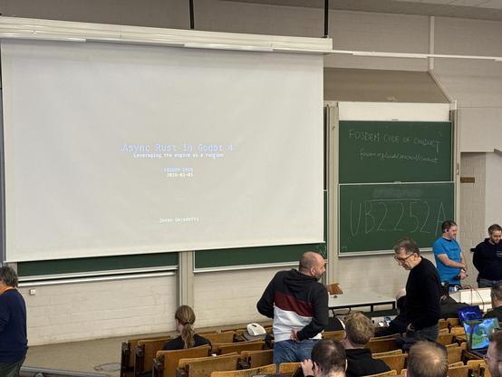 Photo of the stage with an almost unreadable screen showing the text Async Rust in Godot 4. 