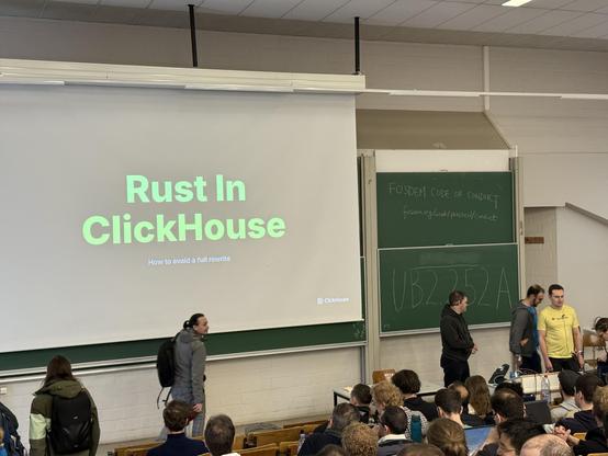 Photo of the stage with a screen showing the title of the talk: Rust in ClickHouse
