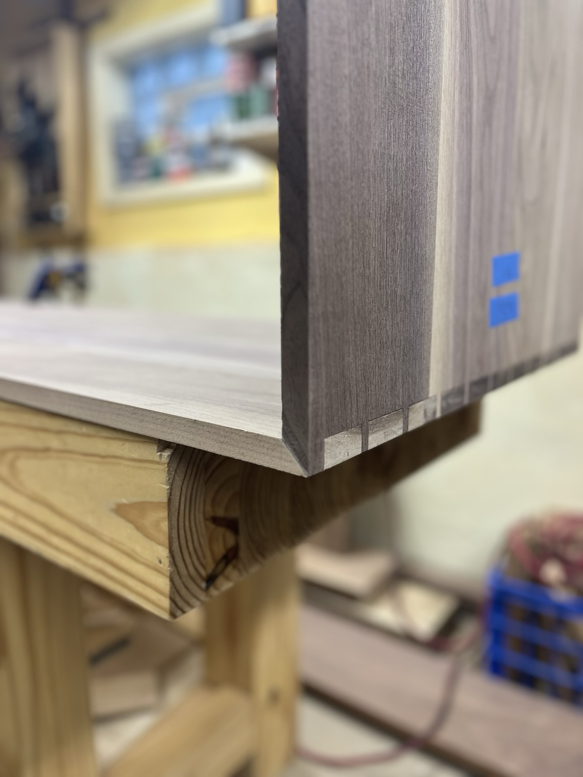 Two walnut panels connect at a 90 degree angle by dovetail joints. The corners are mitered.