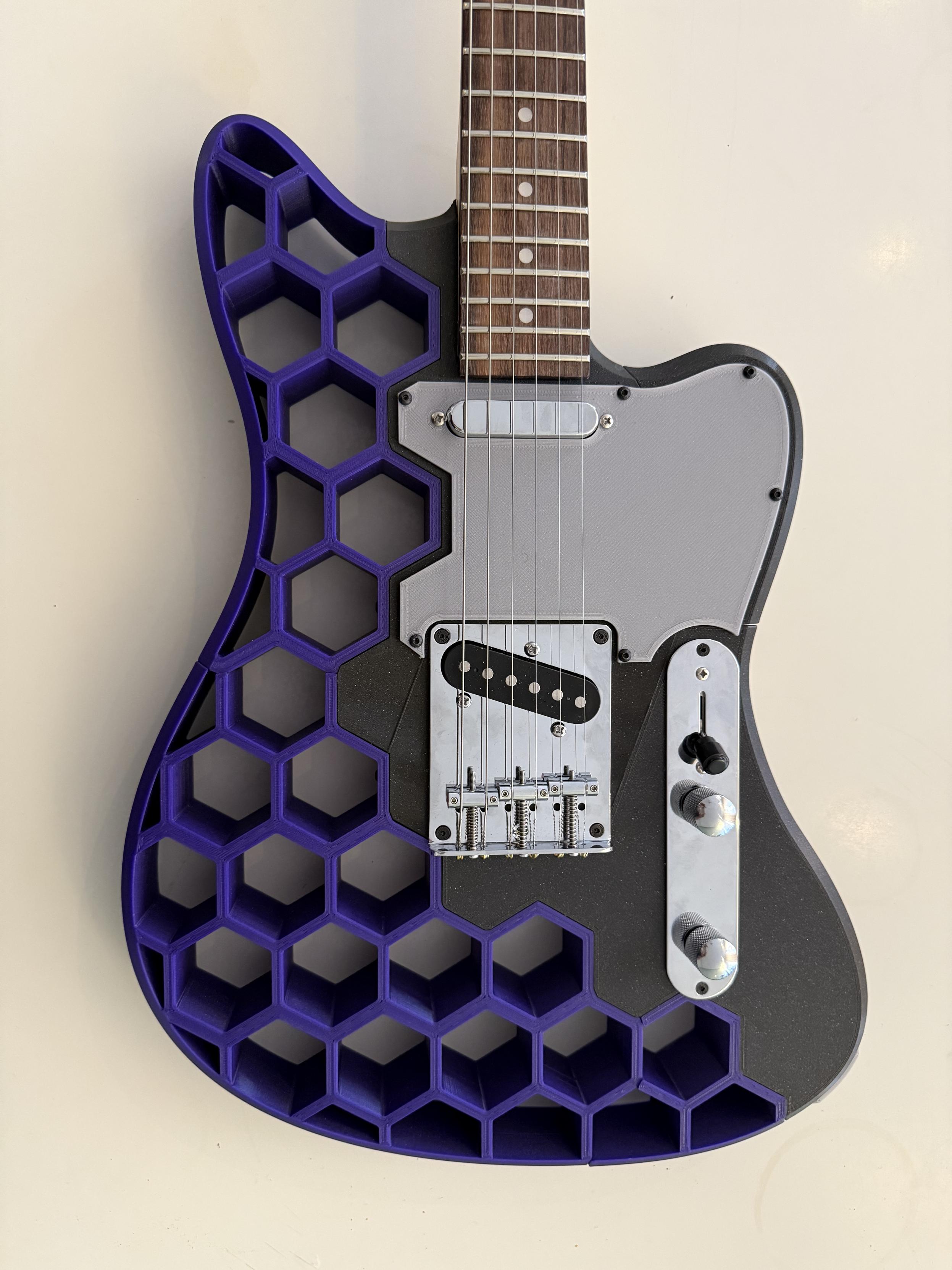 Photo of the body of a purple and black 3D printed guitar with a gray pickguard.