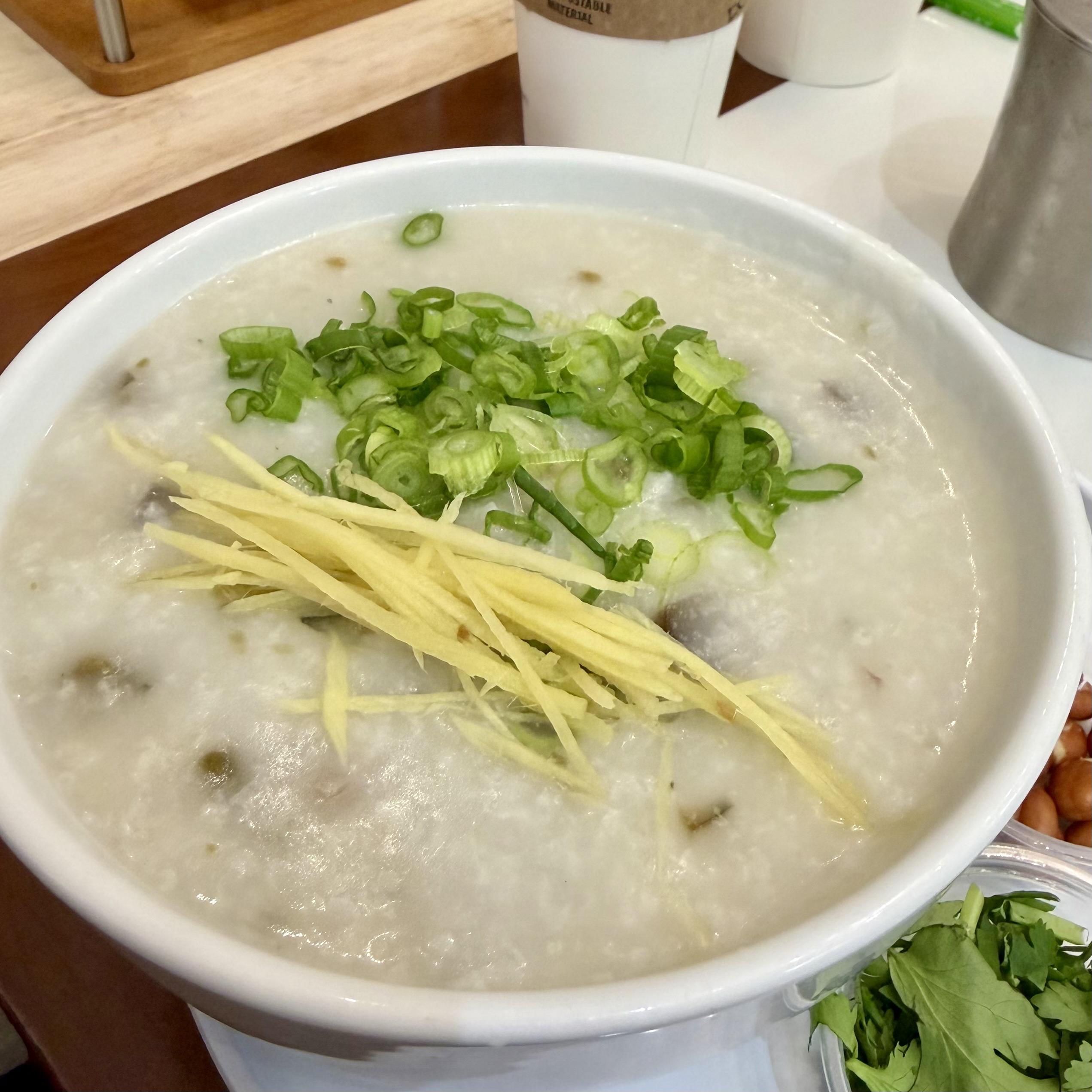 A photo of Cantonese congee with slivers of ginger and scallions