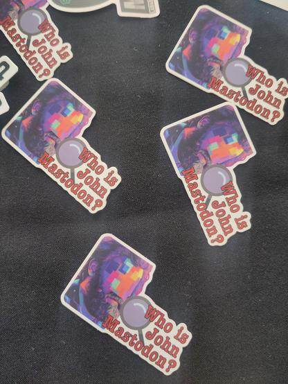 Several stickers at odd angles that say "Who is John Mastodon?"