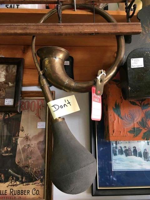 an antique horn with a rubber bulb on one end, with a tag taped to it that simply says "Don't"