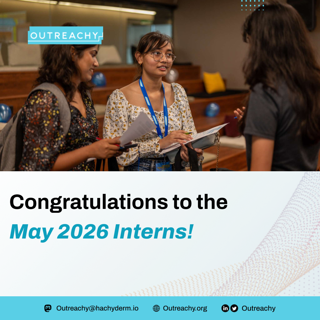 Three young women stand together in a collaborative indoor setting, engaged in conversation while holding notebooks and papers. One woman wearing glasses and a lanyard appears to be explaining something as the others listen. The Outreachy logo is displayed at the top. Bold text on the image reads, “Congratulations to the May 2026 Interns!” with additional contact details and social icons shown at the bottom, celebrating the newly selected cohort