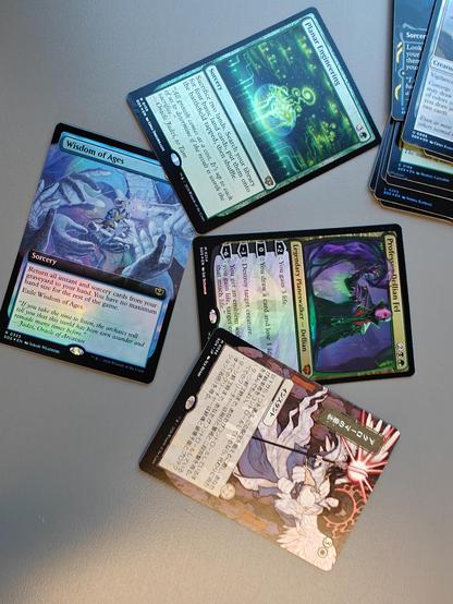 Four foil Magic: The Gathering cards. One is written in Japanese. The art is awesome and I barely understand the text on the others. Something along the lines of "do awesome stuff".