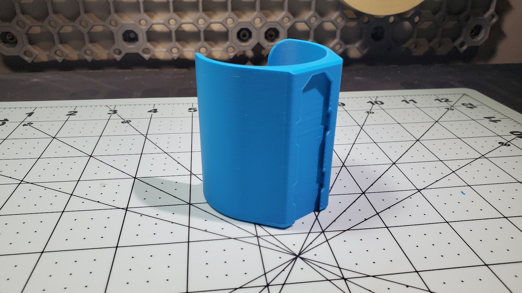 A cyan 3D printed cylindrical sleeve, back facing the camera, with a groove along the face for attaching to a Multiboard panel