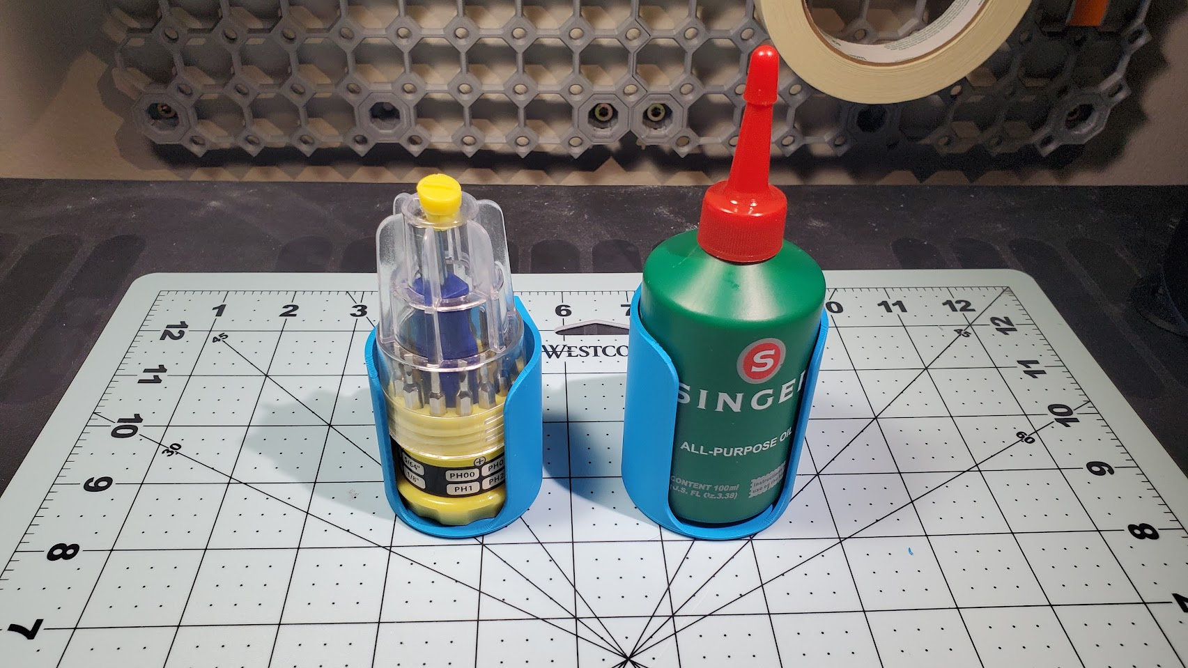Two of the cylindrical sleeves; one holding a mini screwdriver set and the other holding a 100ml Singer machine oil bottle