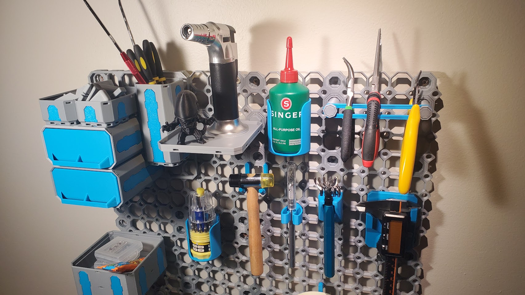 A grey Multiboard panel with cyan accents, displaying various tools and bins; among them, the mini screwdriver set and Singer bottle