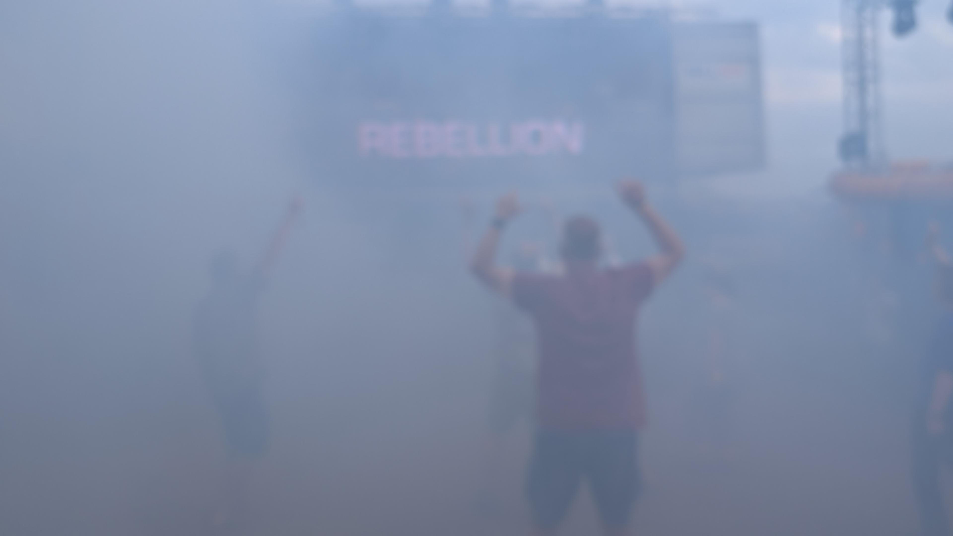 a hazy foggy picture, a silhouetted figure with arms raised and led text reading REBELLION