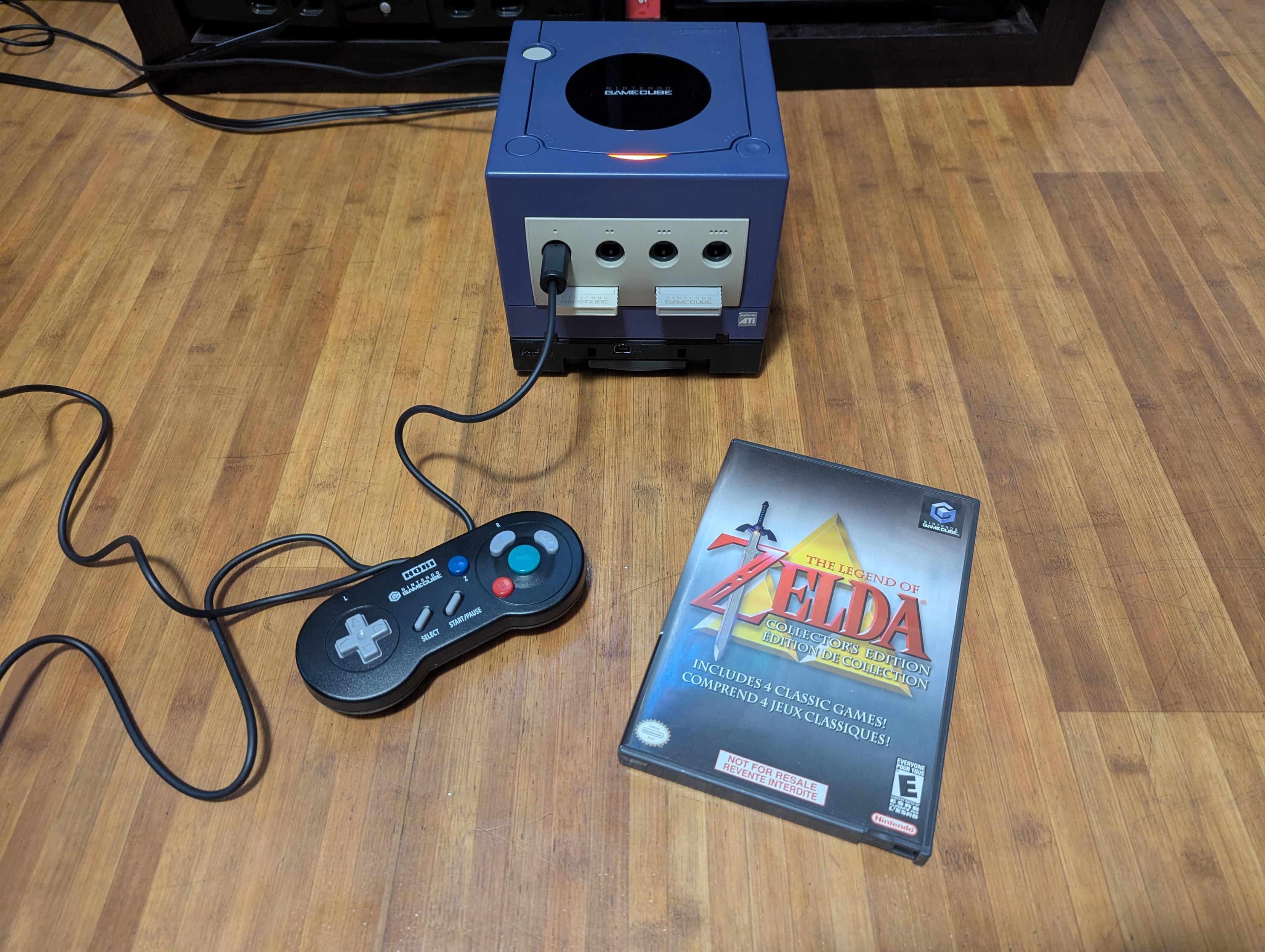 My GameCube on the floor, power light on, Hori Gameboy Player controller in port 1, the case for the Zelda Collectors Edition disk next to it