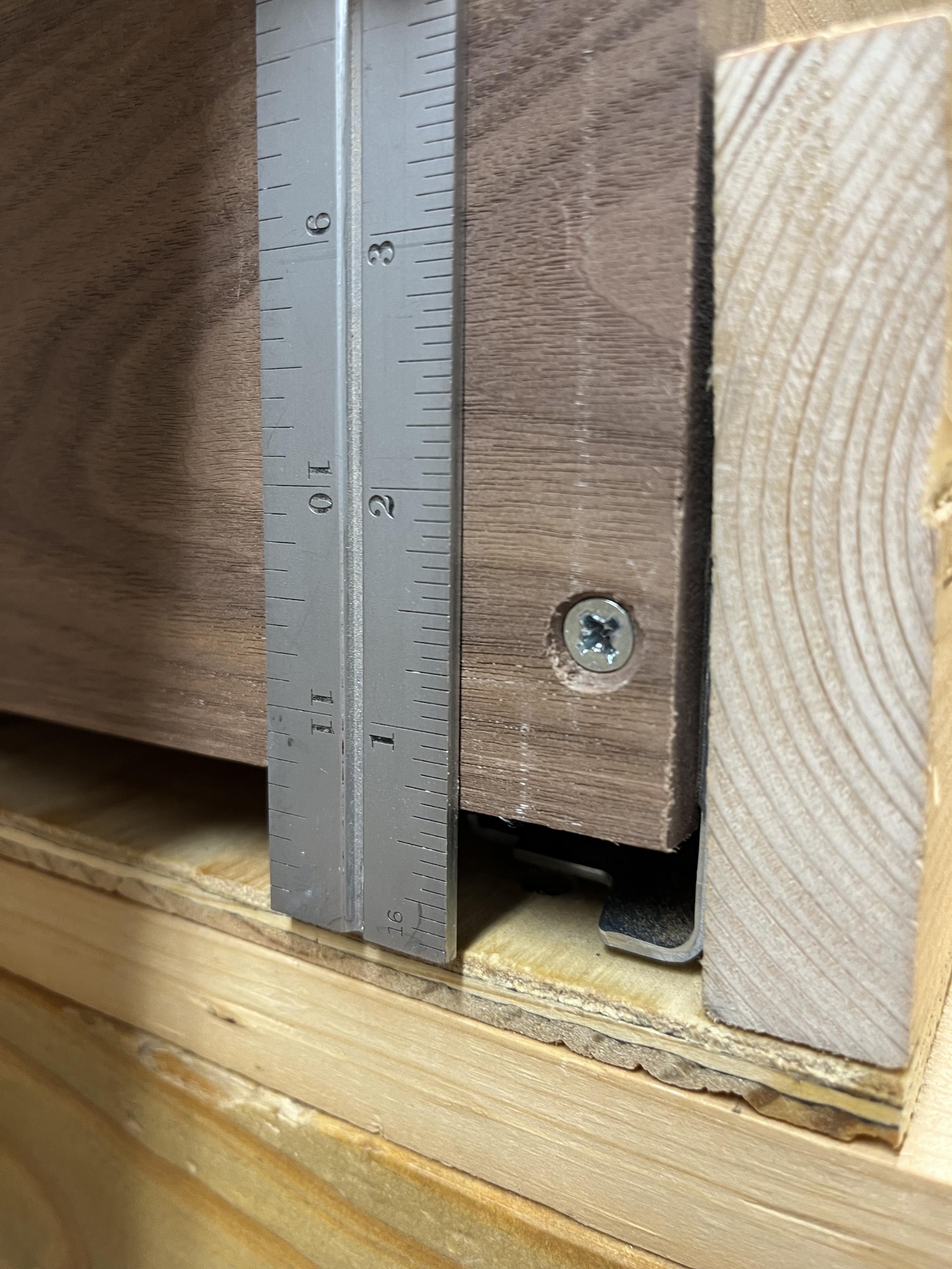 The face of a walnut board with a gap below it as it sits in a box. A ruler is held against the face showing that the gap is a little more than 5/8".