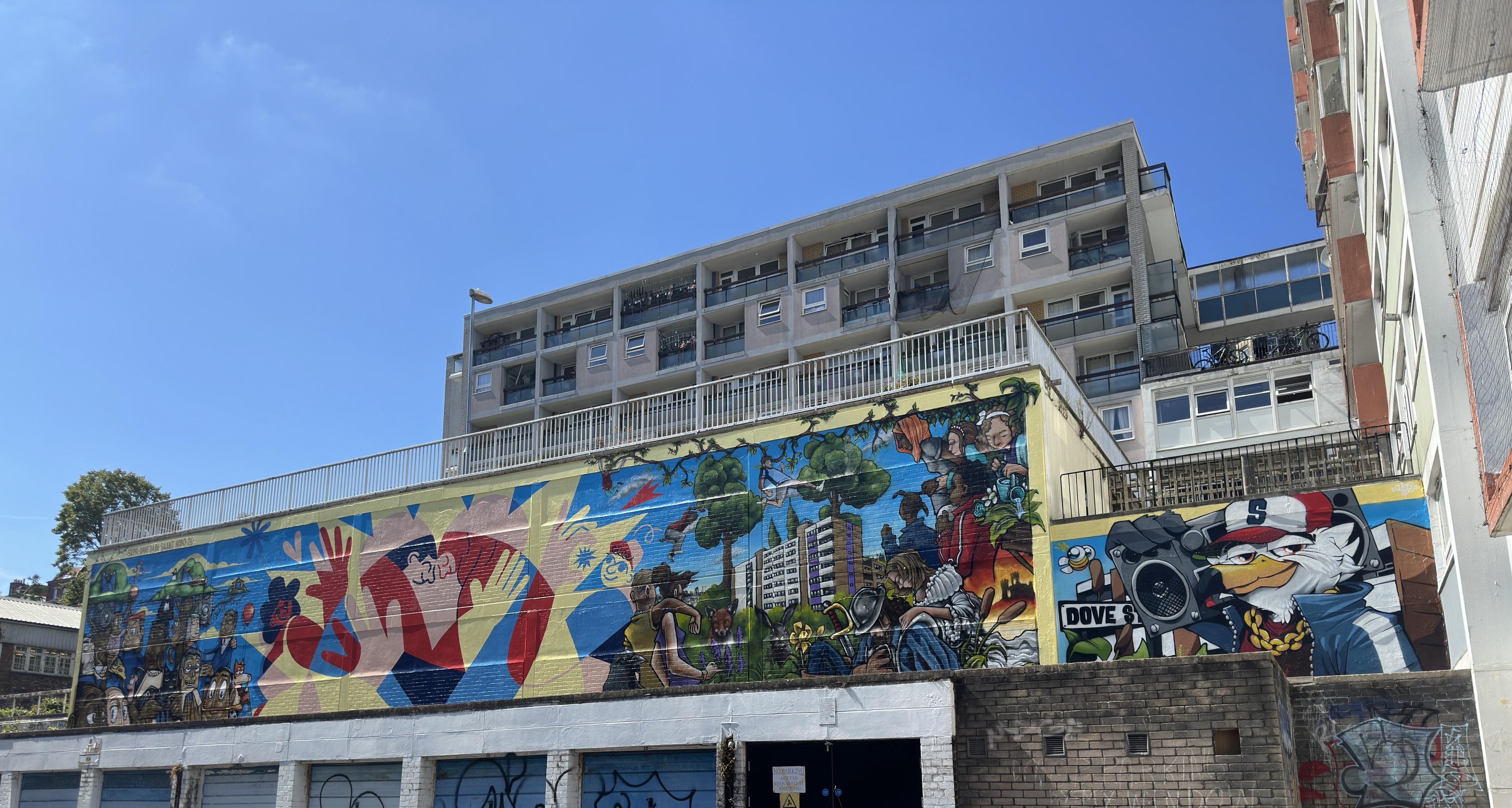Can afford murals in front of a tower block. Some of the murals represent the building and the residents.