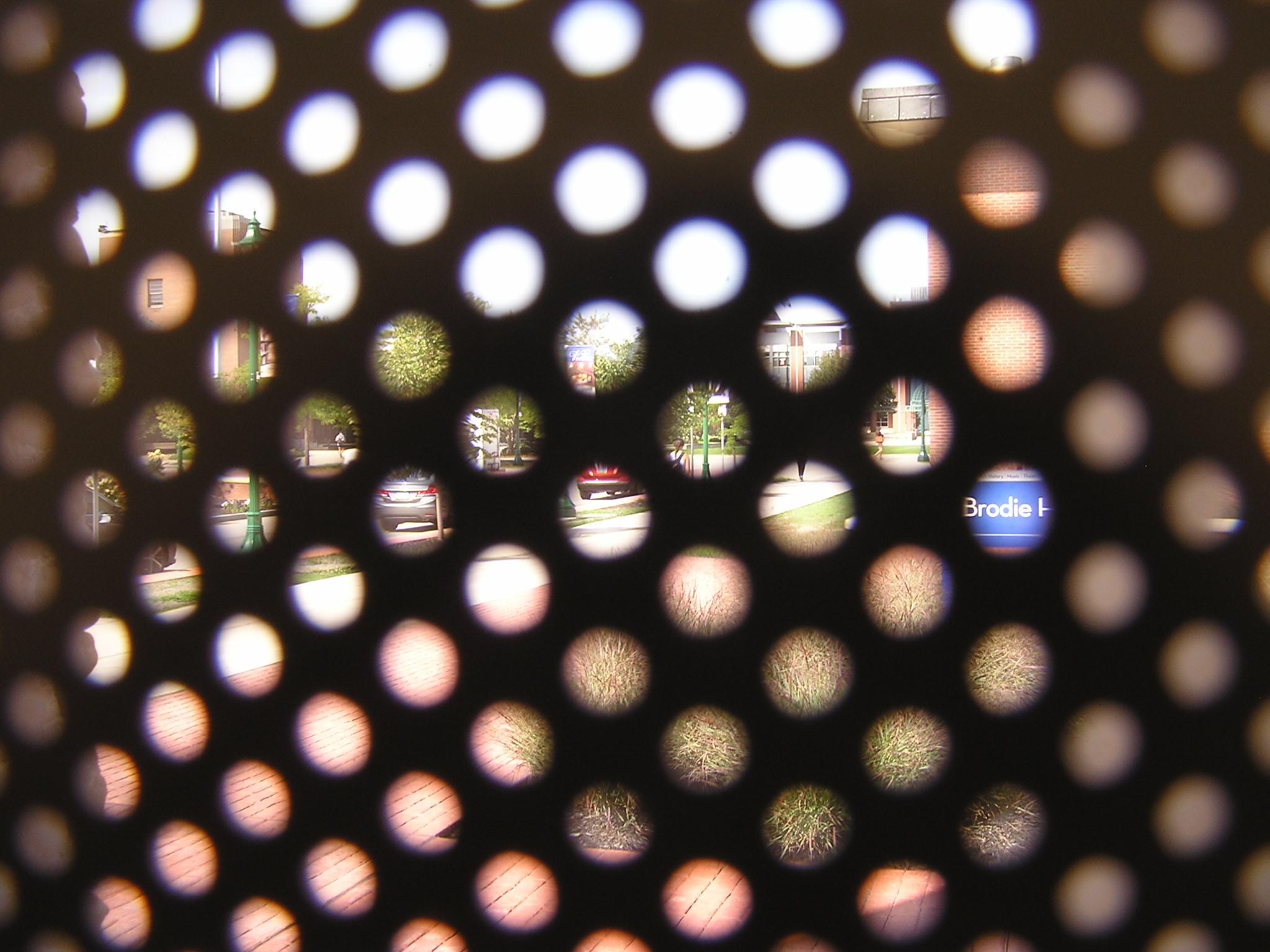 A college campus, taken through a shade with circular perforations